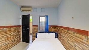 Un dormitorio con cama, ventana con cortinas azules, puerta y pared con diseño estampado.