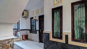 Un pasillo con pared de piedra, suelo de baldosas, banco de madera y puerta con ventanal.