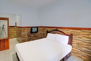 A hotel room with a large bed, a wooden headboard, a television on a stand, and a camera on a tripod. - OYO 91678 Citarum Guest House (Denpasar)