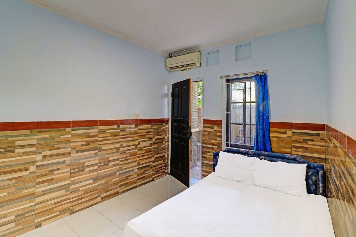 Un dormitorio con una cama, una ventana con cortinas azules, una puerta y una pared con diseño estampado.