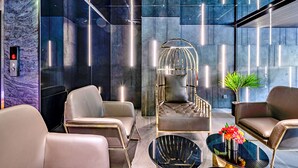 Un espace de détente moderne avec des canapés en cuir, un fauteuil original doté d’une structure métallique et une table basse en verre.