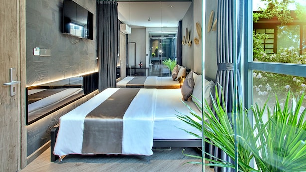 Une chambre d’hôtel moderne avec deux lits, une grande fenêtre et une vue sur la verdure environnante.