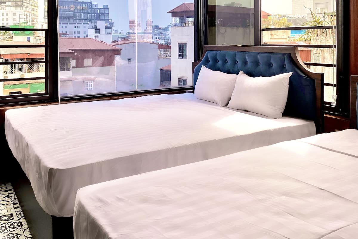 A hotel room with two beds, large windows, and a view of the cityscape.