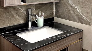 Een badkamer met een donker houten wastafelmeubel, een witte wastafel en een spiegel erboven.