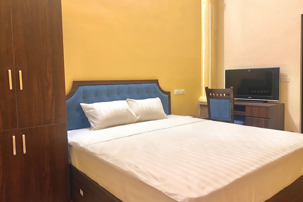 A hotel room with a bed, a wardrobe, a television, and a chair.