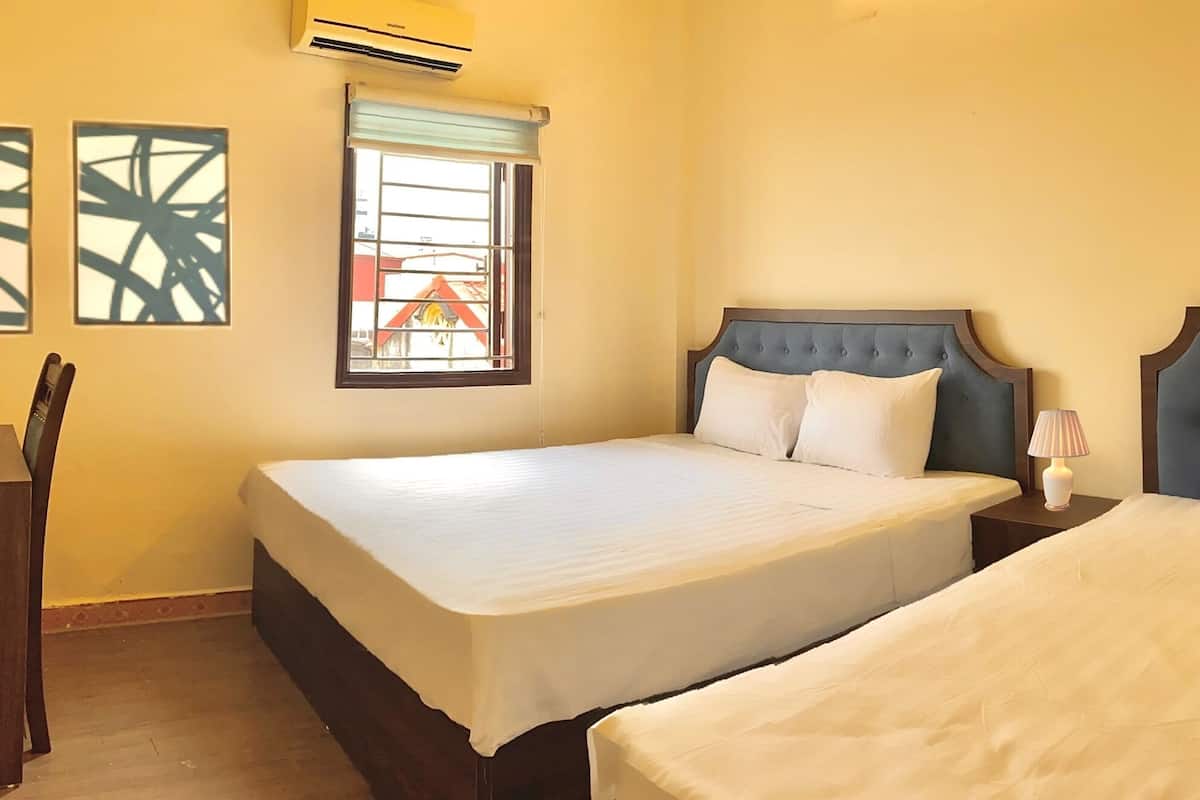 A hotel room with two beds, a desk, and a chair.