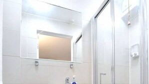 Un baño con inodoro, lavamanos y ducha con mampara de vidrio.