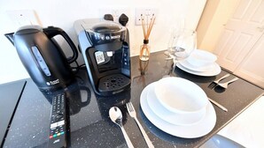 Una encimera de cocina con cafetera, hervidor y un control remoto JVC.