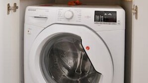 Lavadora blanca compacta con panel de control y una etiqueta roja en la parte frontal.