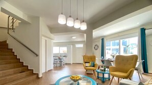 A spacious living room with a staircase, a dining area, and a kitchen in the background. - CostAnita Beach House in Almyrida (Almirida)