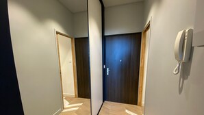 Un pasillo con piso de madera, un teléfono en la pared y una puerta con panel de madera oscura.