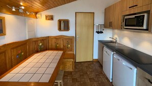 A compact kitchen with wooden cabinets, a microwave, a sink, and a dishwasher. - Les Saisies Apt, 4 pers, south balcony, near slopes (Les Saisies)