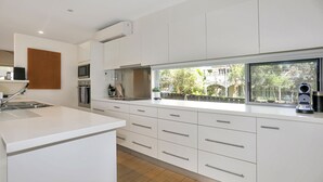 A modern kitchen with white cabinetry, a built-in oven, and a window overlooking a garden. - The Sanctuary - a tranquil hidden oasis (Hawks Nest)