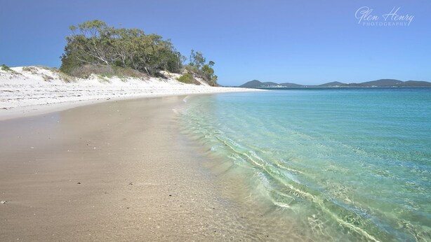 A beach with clear shallow waters, white sand, and a line of trees on the left. - The Sanctuary - a tranquil hidden oasis (Hawks Nest)