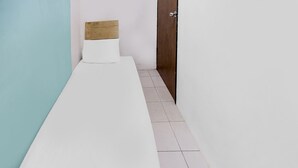 A narrow, single-bed room with a wooden headboard, white bedding, and a closed door. - Hotel O Solo Baru Homestay Syariah (Batam)
