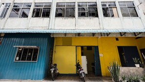 A building with a blue door and yellow walls, a motorcycle parked in front, and a sign on the yellow wall. - Hotel O Solo Baru Homestay Syariah (Batam)