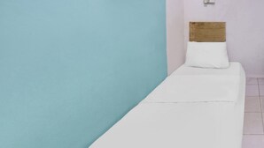 A single bed with a wooden headboard and white bedding in a room with light blue and white walls. - Hotel O Solo Baru Homestay Syariah (Batam)