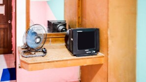A small room with a wooden shelf holding a fan and a black television. - Hotel O Solo Baru Homestay Syariah (Batam)