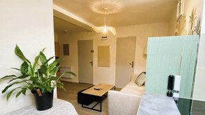 Une petite pièce agréable et chaleureuse, avec un lit, une table de chevet, une chaise et une plante en pot.