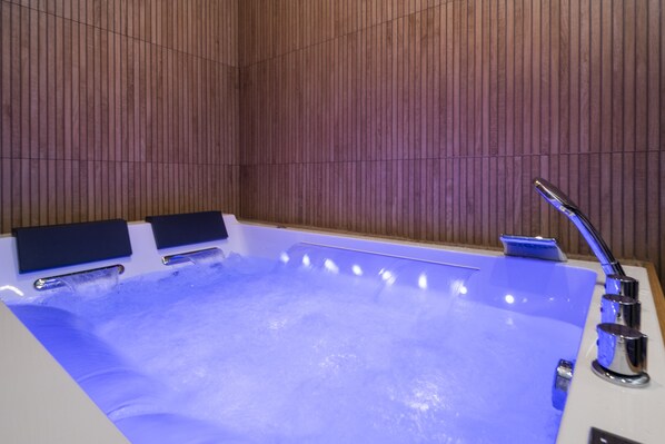 A hot tub with a wooden wall backdrop and a modern faucet. - Art Deco Champagne & Spa (Reims)