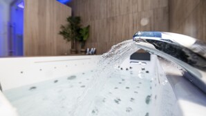 A close-up of a modern bathroom with a running water faucet.