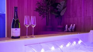 A bottle of champagne and two glasses on a counter with a water feature.