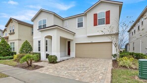 A two-story residential building with a garage, a front porch, and a brick driveway. - Luxury Contemporary Style House on Solara Resort, Orlando House 6149 (Kissimmee)