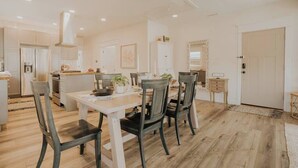 Une cuisine moderne avec des meubles blancs, une table à manger avec des chaises et un ventilateur de plafond.