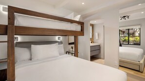 Een moderne hotelkamer met een stapelbed, een klein nachtkastje met een vaas, en uitzicht op de tuin door een raam.