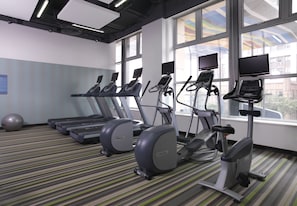 A gym with treadmills, elliptical machines, and a stationary bike, large windows, and a striped carpet. - Funiu Mountain Hotel (Zhengzhou)