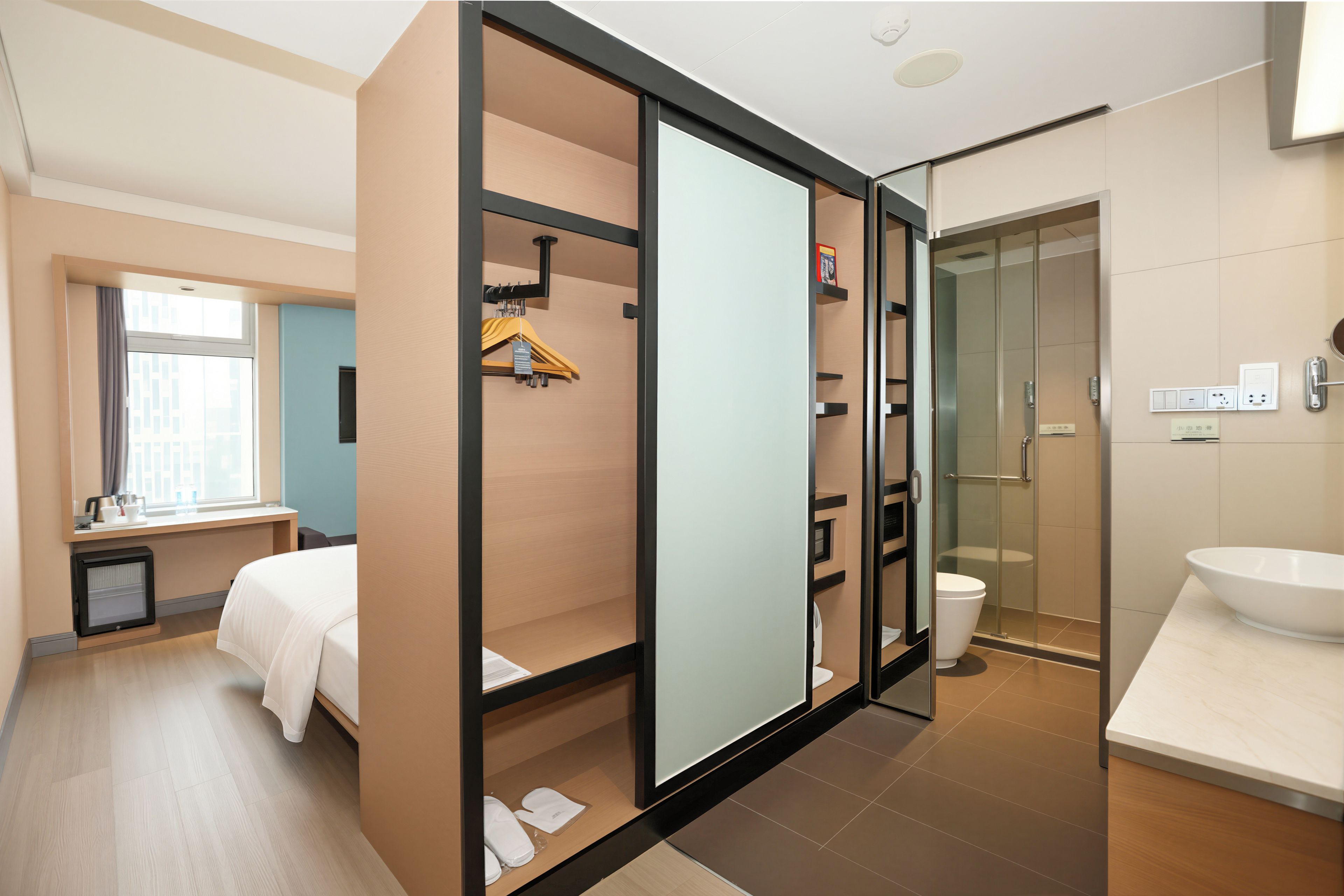 A hotel room with a bed, a bathroom with a shower, and a sink.