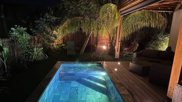 A swimming pool with a wooden deck and lounge chairs, surrounded by tropical plants and a covered seating area. - Belle Villa Avec Piscine à 200m de la Plage ! (Saint-Leu)