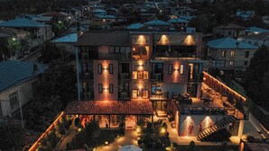 A multi-story hotel with a rooftop terrace, outdoor seating area, and a swimming pool.
