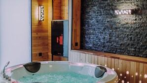 A hot tub with a wooden interior and a stone wall.