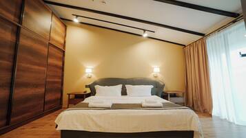 Una habitación de hotel moderna con una cama grande, un armario de madera y dos lámparas de noche.