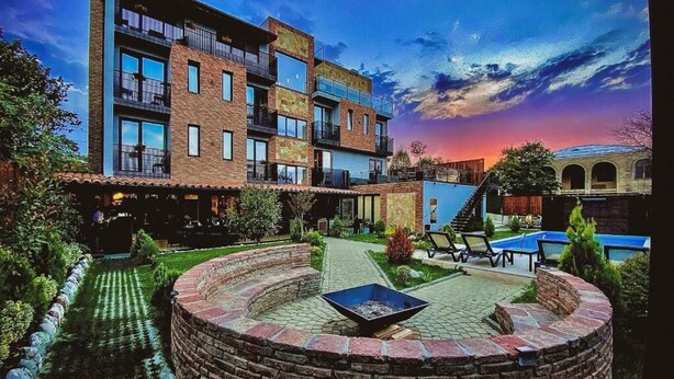 A courtyard with a circular brick fire pit, a pool, and a multi-story building with balconies.