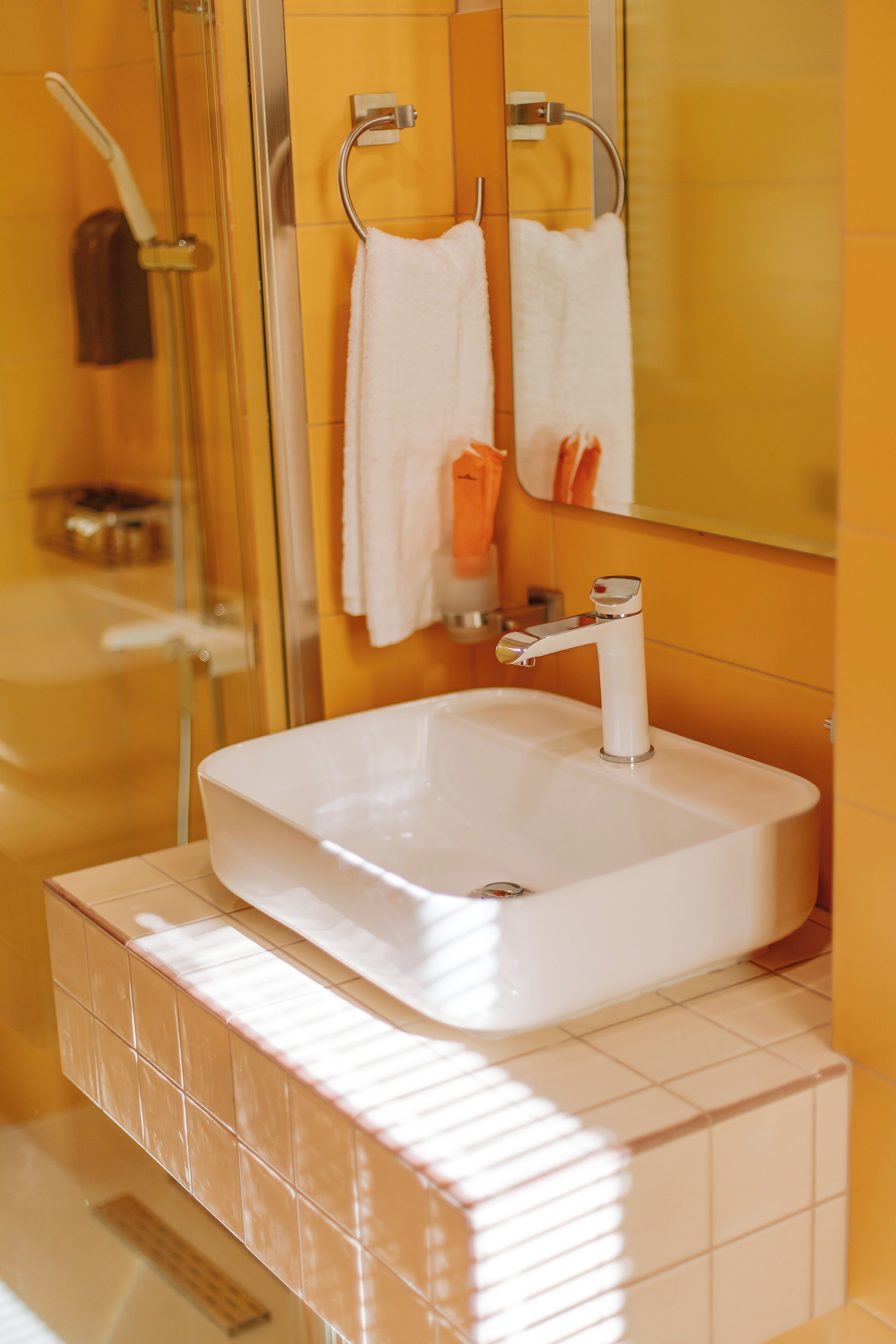 Un baño con un lavabo blanco, cabina de ducha de cristal y un espejo sobre el lavabo.