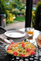 Una comida sobre la mesa, con un vaso de jugo de naranja, un plato de comida y una servilleta.