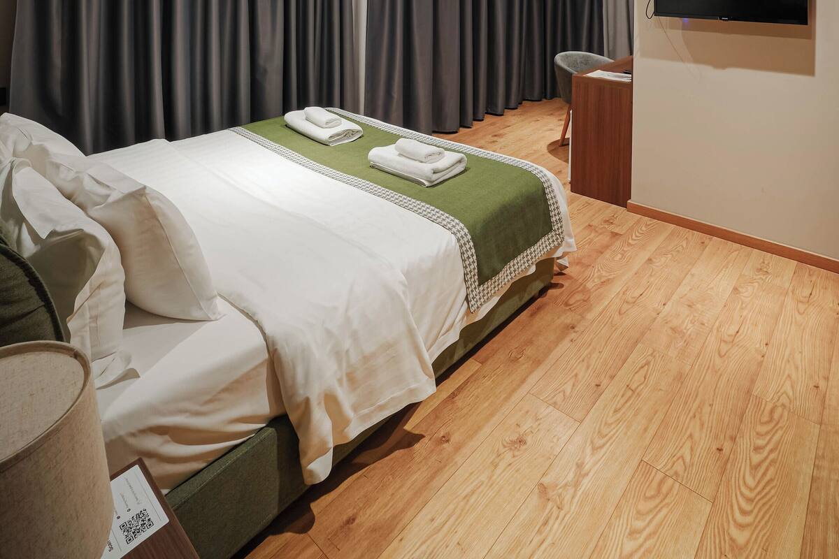 Habitación de hotel con cama, televisión y suelo de madera.