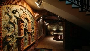 A dimly lit hallway with brick walls and a patterned rug.