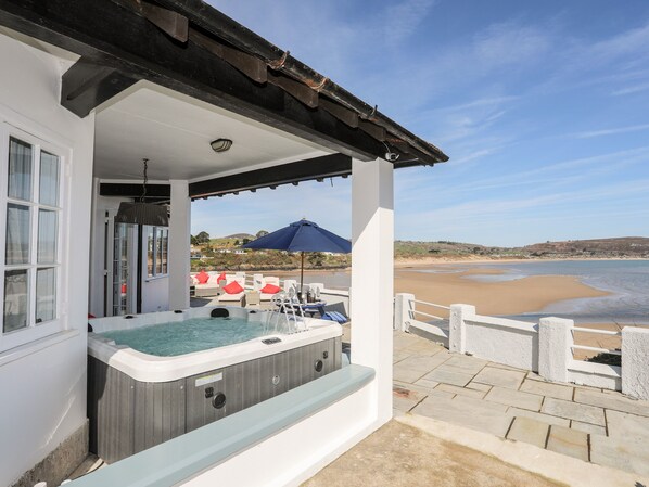 A hot tub on a balcony with a view of a beach and ocean.
