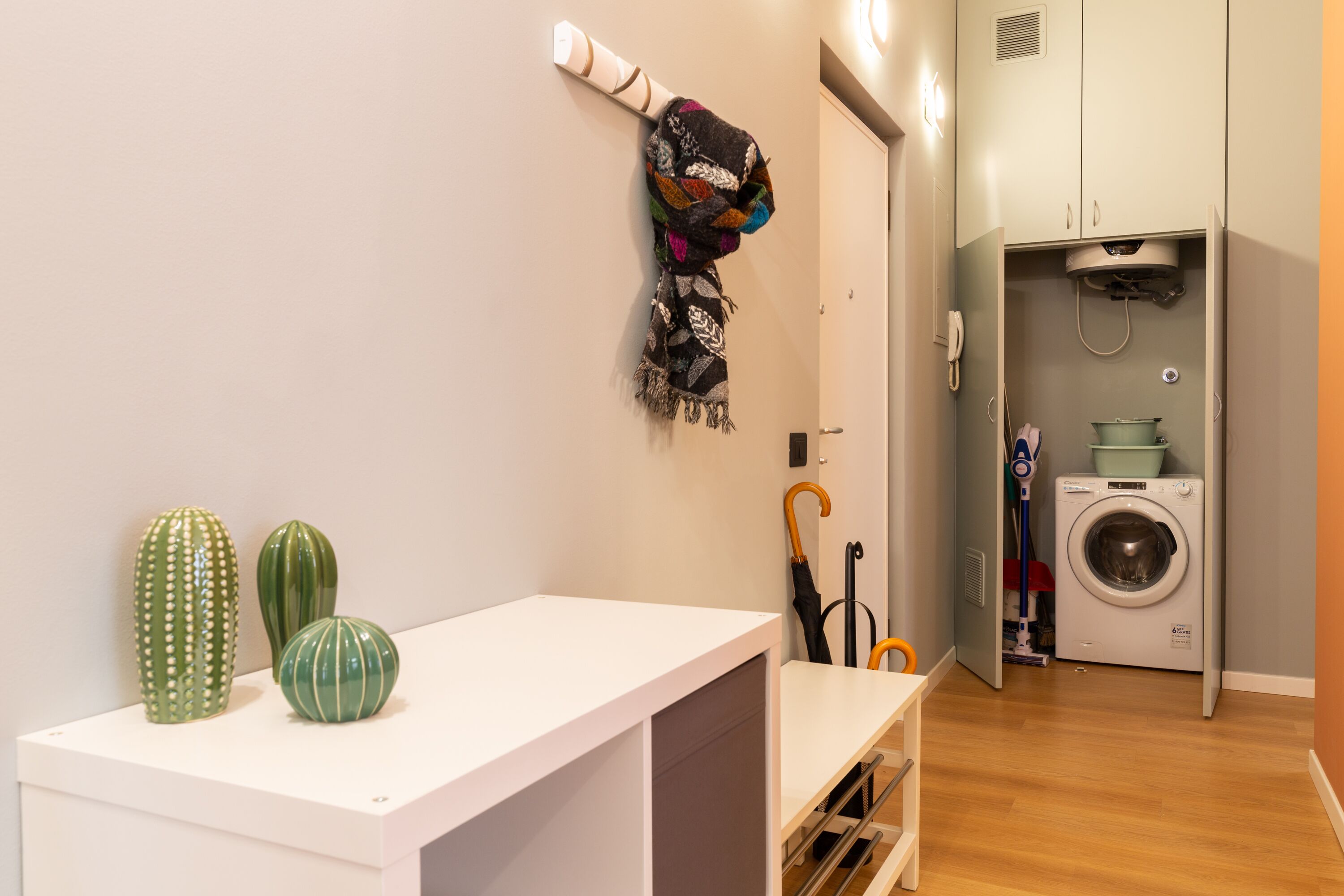 Una habitación pequeña y limpia con una mesa blanca, una lavadora y un tendedero.