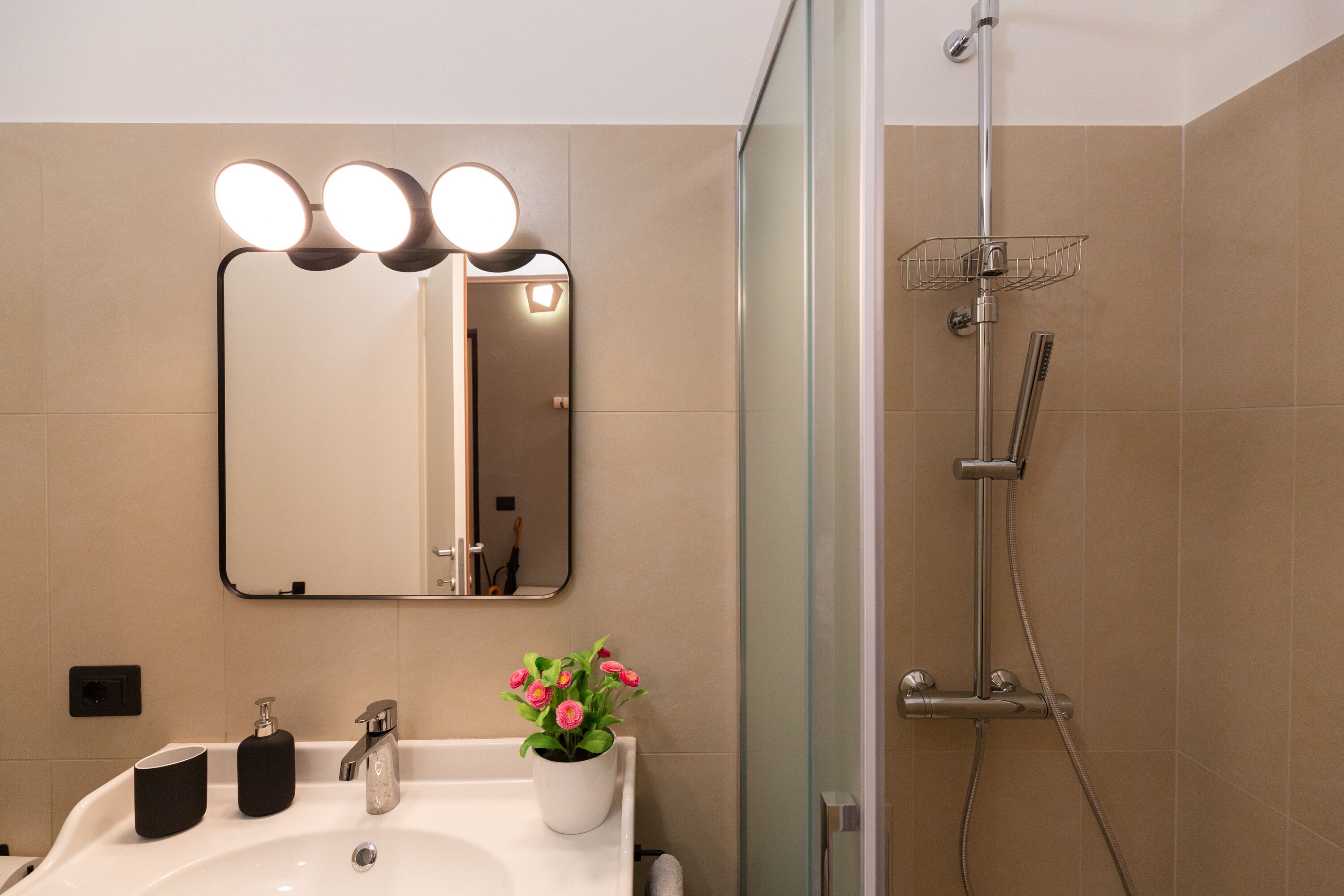 A bathroom with a sink, mirror, and shower.