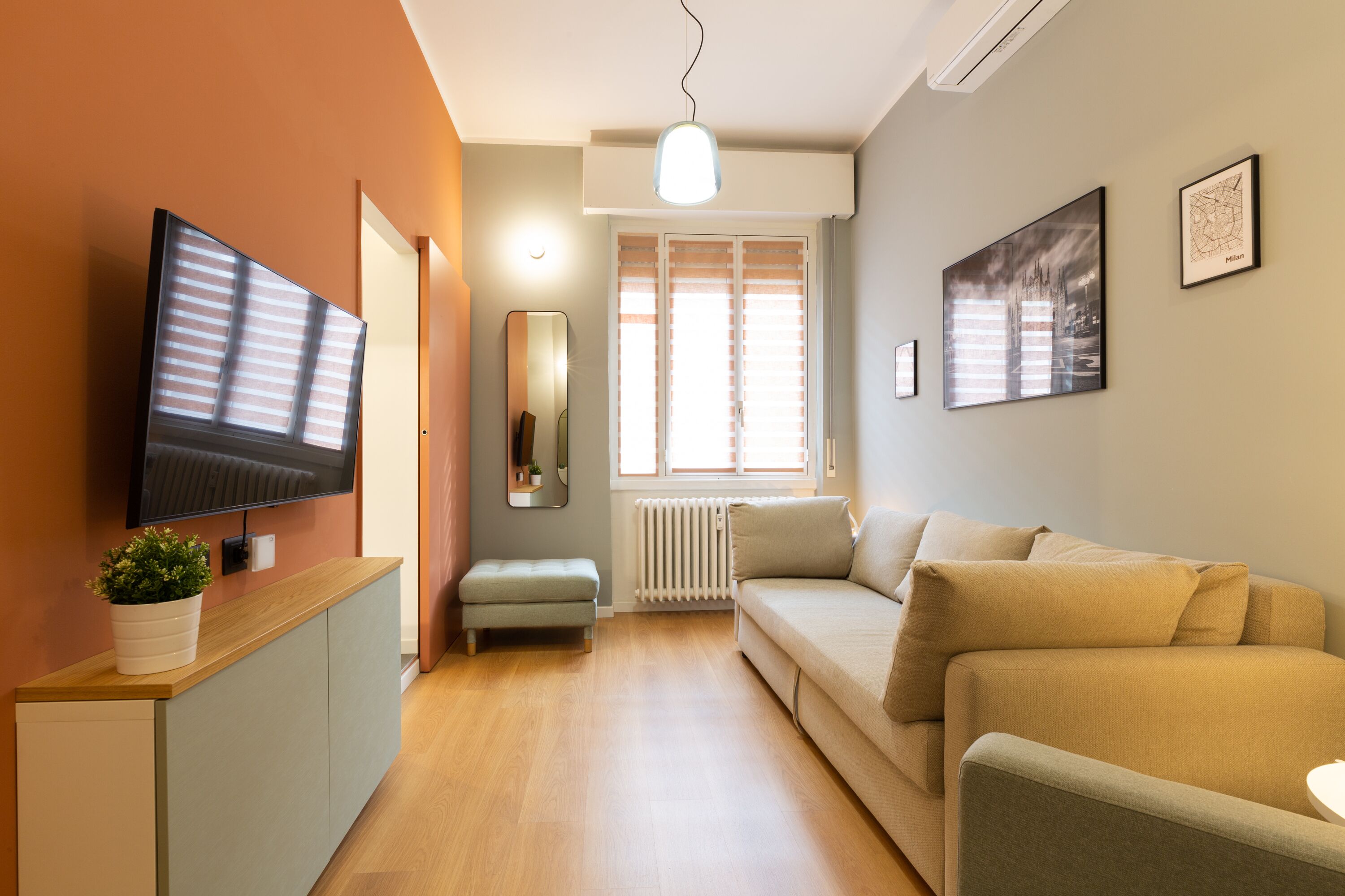 Ein modernes Wohnzimmer mit Flachbildfernseher, einer Couch, einem Couchtisch und einer Topfpflanze.