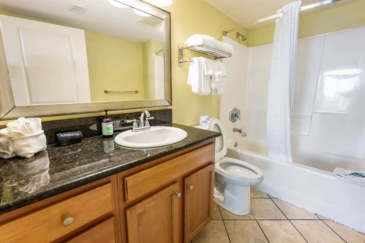 A bathroom with a sink, mirror, towel rack, toilet, and bathtub.