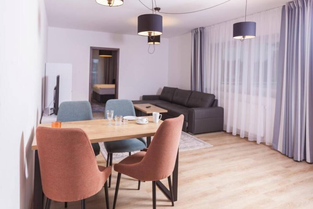A modern living room with a wooden dining table, two sofas, and a TV.