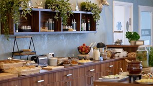 Disposição de buffet com diversos alimentos, cestas e uma prateleira com plantas e objetos decorativos.