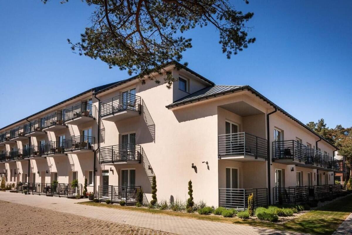 A multi-story hotel with balconies, a paved driveway, and a clear sky.