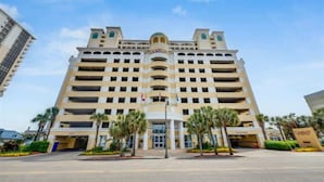 A multi-story hotel with a central entrance, palm trees, and a clear sky. - King Suite 3BR,Direct Oceanfront Views, Remodeled! (Myrtle Beach)