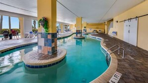An indoor swimming pool with tiled walls and a brick border, surrounded by yellow pillars and a covered roof. - King Suite 3BR,Direct Oceanfront Views, Remodeled! (Myrtle Beach)